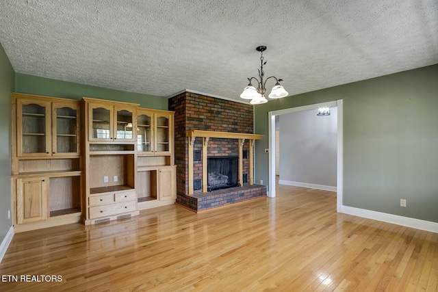 unfurnished living room featuring light wood finished floors, baseboards, and a textured ceiling