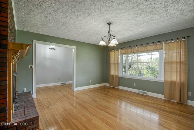 spare room featuring visible vents, a chandelier, and wood-type flooring