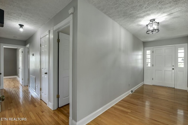 entrance foyer featuring visible vents, light wood-style flooring, baseboards, and a textured ceiling