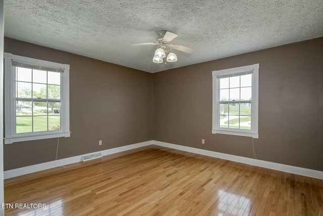 spare room featuring plenty of natural light, baseboards, visible vents, and light wood-style flooring