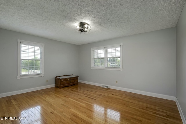 spare room featuring light wood-type flooring, baseboards, and visible vents
