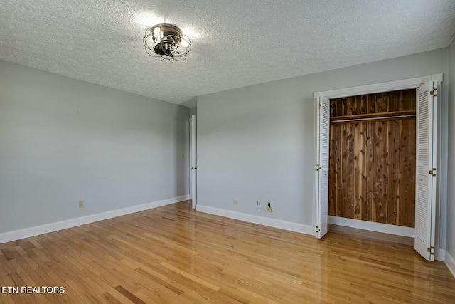 unfurnished bedroom featuring light wood-type flooring, baseboards, and a textured ceiling