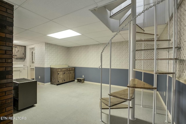 basement featuring baseboards, wallpapered walls, and a paneled ceiling