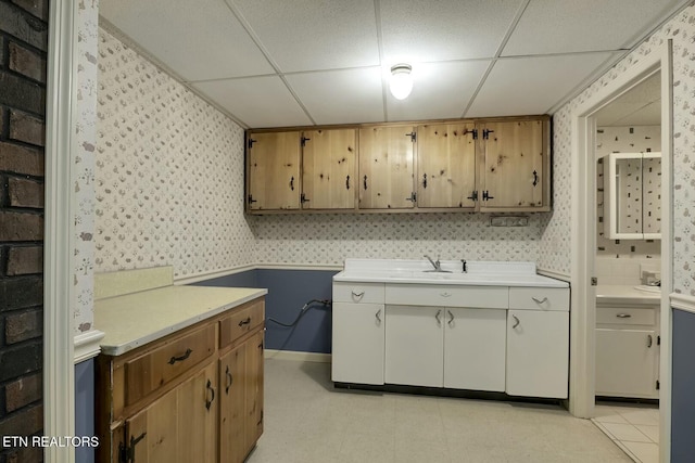 laundry area with wallpapered walls, wainscoting, light floors, cabinet space, and baseboards