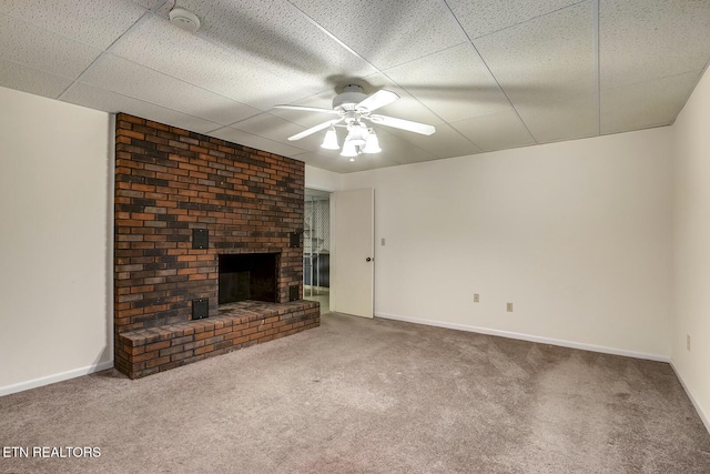 unfurnished living room with a brick fireplace, carpet flooring, baseboards, and ceiling fan