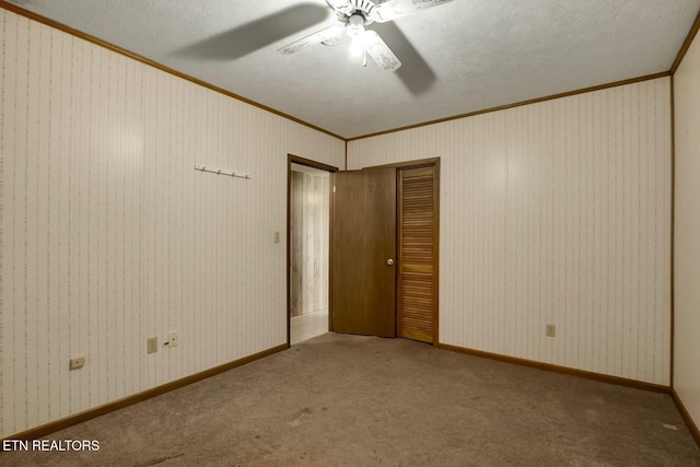 unfurnished bedroom featuring carpet, a closet, ceiling fan, and crown molding