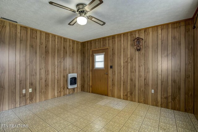 unfurnished room featuring ceiling fan, wood walls, tile patterned floors, and heating unit