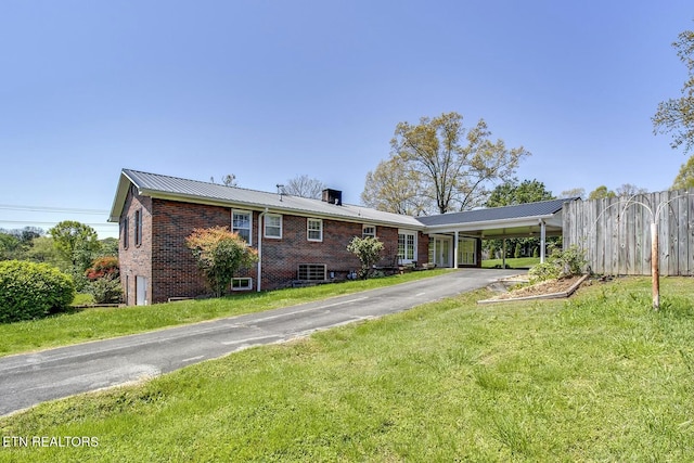 view of front of house with a front lawn, brick siding, fence, and metal roof