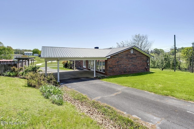 exterior space with brick siding, a front lawn, aphalt driveway, and metal roof
