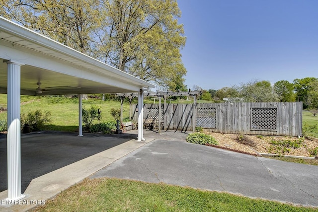 view of car parking featuring fence and a ceiling fan
