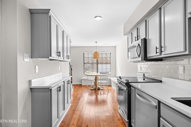 8411 Ivy Green Way, Knoxville, TN 37919 - kitchen with light wood finished floors, backsplash, gray cabinets, baseboards, and appliances with stainless steel finishes
