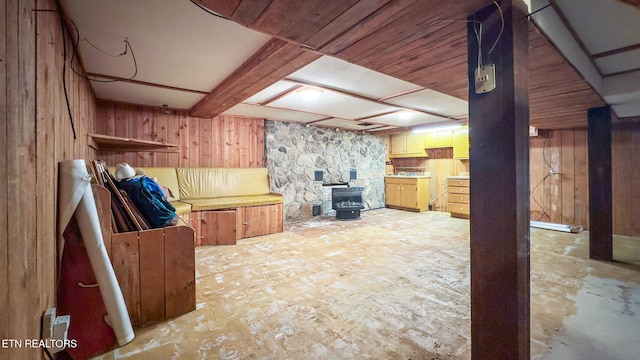 finished basement featuring wood walls and a wood stove