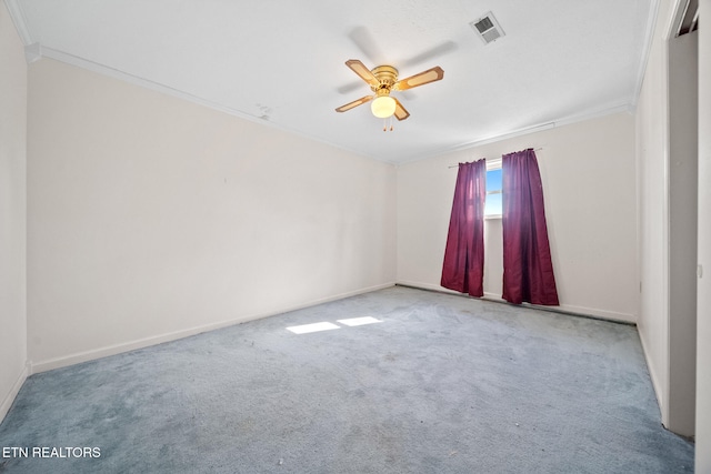 carpeted spare room featuring visible vents, baseboards, ornamental molding, and a ceiling fan