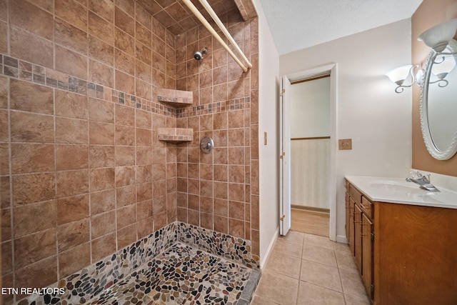 full bathroom with tile patterned floors, tiled shower, vanity, and baseboards
