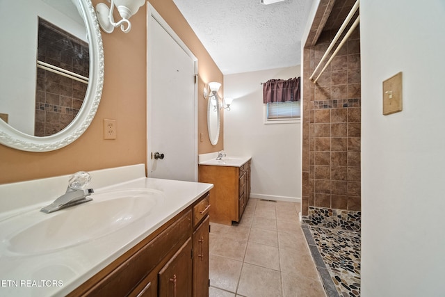 full bathroom featuring a sink, tile patterned floors, a tile shower, and a textured ceiling