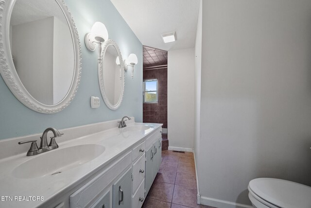 bathroom featuring a sink, toilet, double vanity, and tile patterned flooring