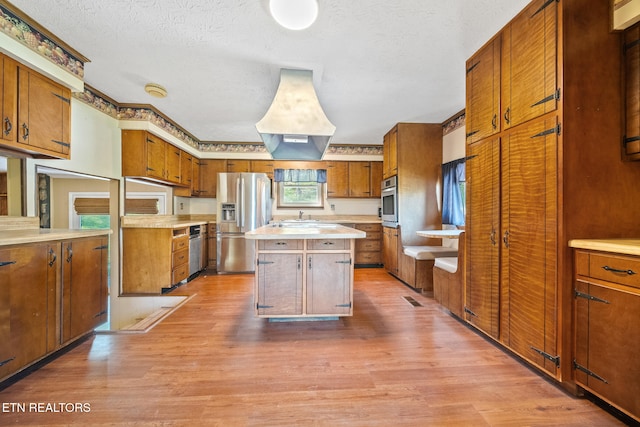 kitchen with brown cabinets, light countertops, light wood-style flooring, and appliances with stainless steel finishes