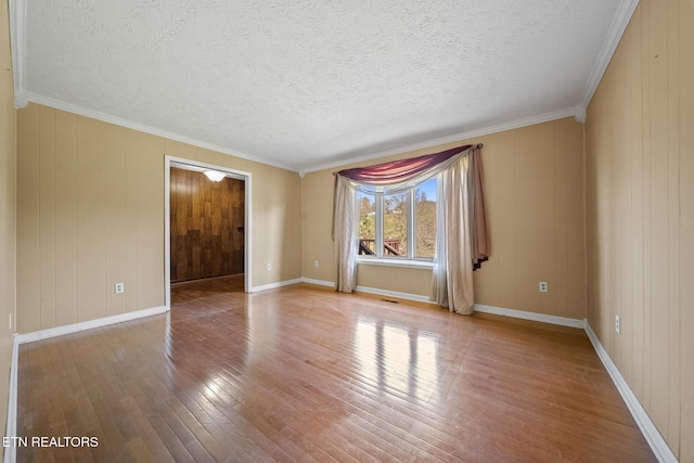 unfurnished room featuring a textured ceiling, crown molding, and wood finished floors
