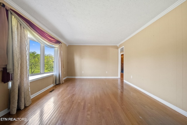 spare room with a textured ceiling, wood finished floors, baseboards, and visible vents