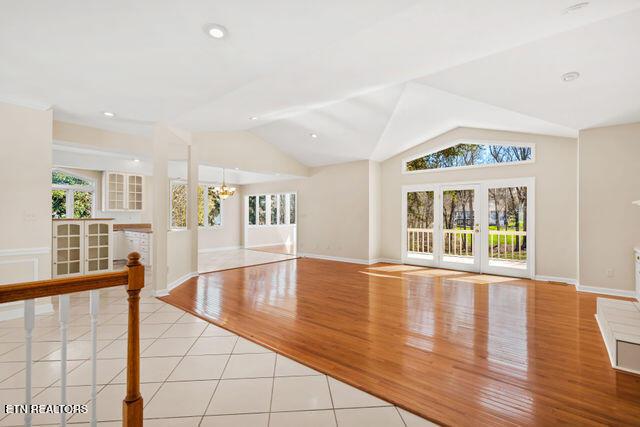 unfurnished living room featuring lofted ceiling, wood finished floors, baseboards, and a notable chandelier