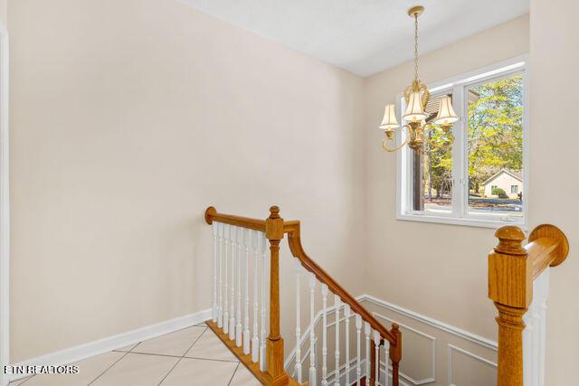 stairway featuring wainscoting, tile patterned flooring, and a chandelier