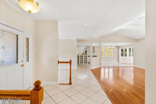 entryway featuring light tile patterned floors, an inviting chandelier, baseboards, lofted ceiling, and recessed lighting