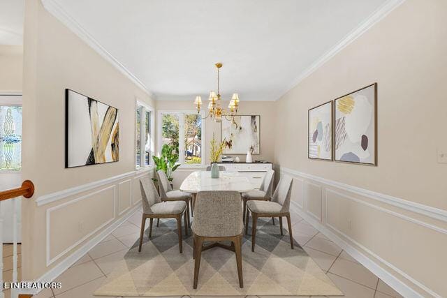 dining area with a decorative wall, a notable chandelier, and crown molding