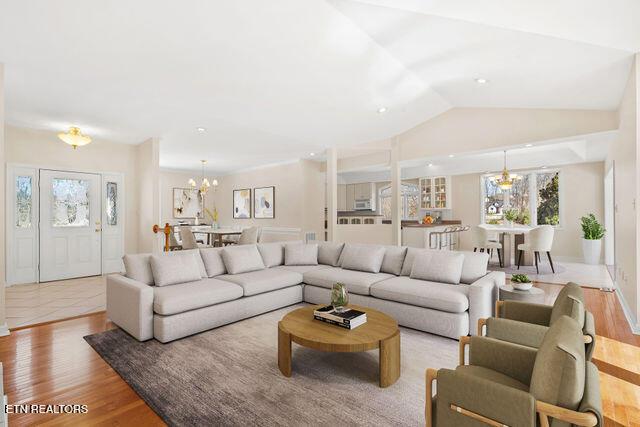 living room featuring lofted ceiling, wood finished floors, and an inviting chandelier