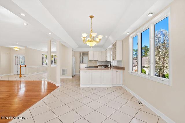 kitchen with light tile patterned flooring, open floor plan, baseboards, visible vents, and a chandelier