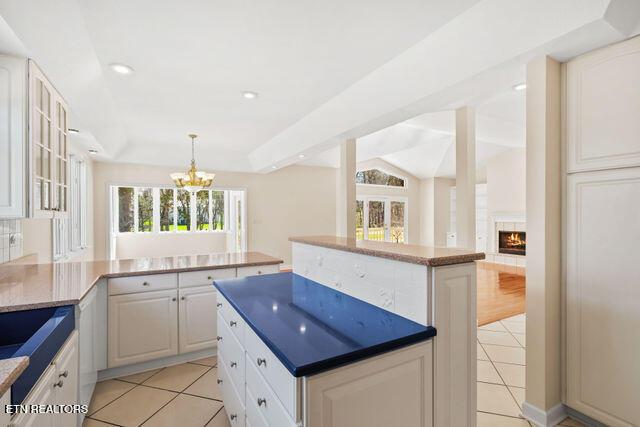 kitchen featuring light tile patterned floors, a peninsula, a notable chandelier, and a kitchen island