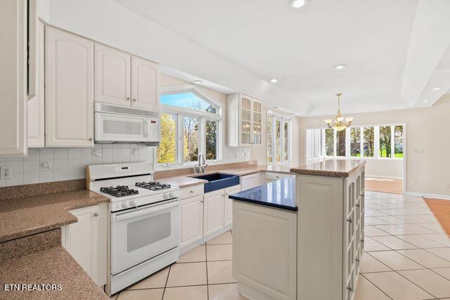 kitchen featuring tasteful backsplash, a sink, a chandelier, white appliances, and light tile patterned floors