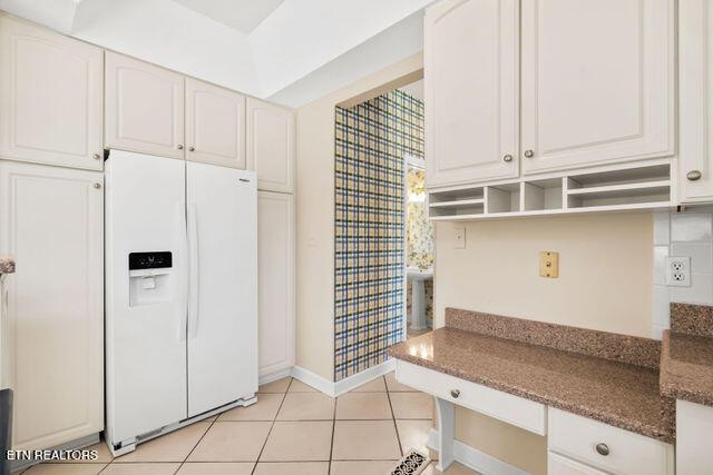 kitchen with open shelves, light tile patterned floors, baseboards, white refrigerator with ice dispenser, and white cabinetry