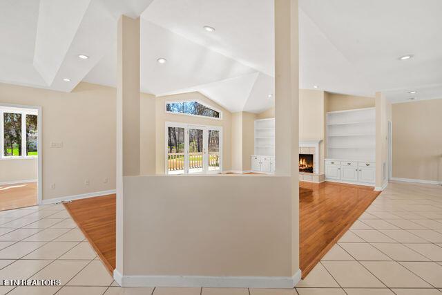 kitchen with baseboards, open floor plan, a lit fireplace, and light tile patterned floors