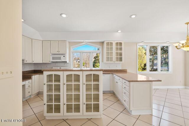 kitchen featuring light tile patterned flooring, white microwave, and glass insert cabinets