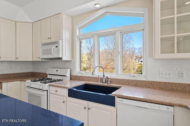 kitchen featuring white cabinets, a sink, and white appliances