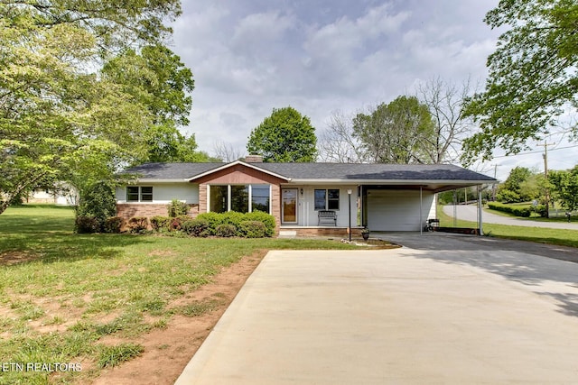 ranch-style home with brick siding, a shingled roof, a carport, a front lawn, and concrete driveway