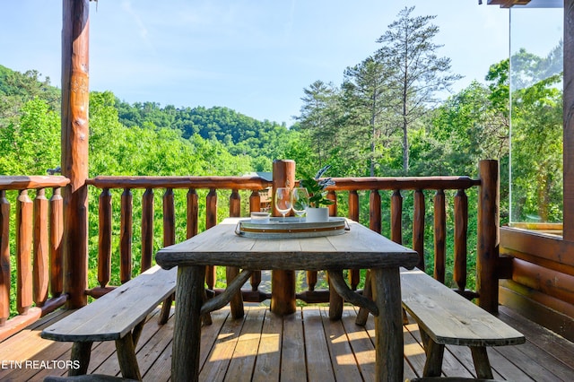 deck with a view of trees and outdoor dining area
