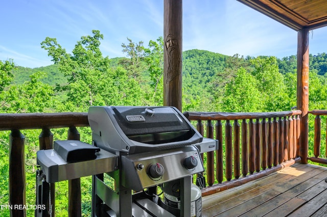 wooden terrace with a wooded view and area for grilling
