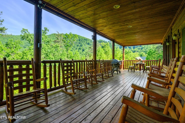 wooden deck featuring a view of trees and outdoor dining space