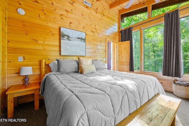 bedroom featuring carpet floors, wood walls, multiple windows, and visible vents