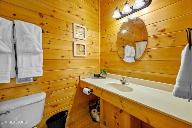bathroom with wood walls, vanity, and toilet