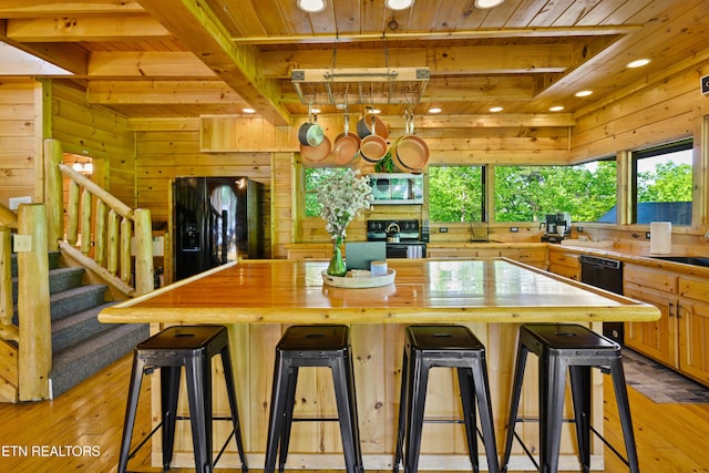 kitchen featuring wooden ceiling, wooden walls, and black appliances