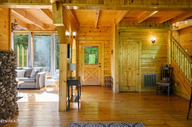 interior space with beam ceiling, visible vents, wood walls, stairs, and wood ceiling