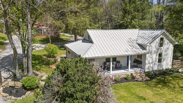 rear view of house with a yard, a porch, a standing seam roof, and metal roof