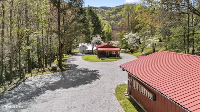 view of property's community with driveway and a wooded view