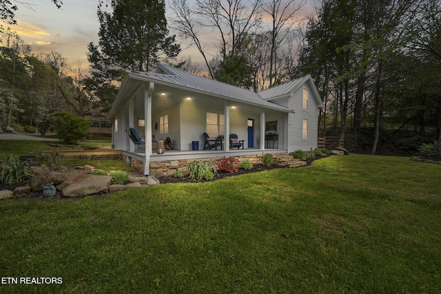 view of front of house with a porch, a front lawn, and metal roof