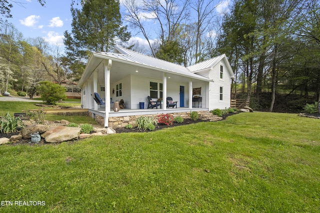 view of property exterior featuring a lawn, covered porch, and metal roof