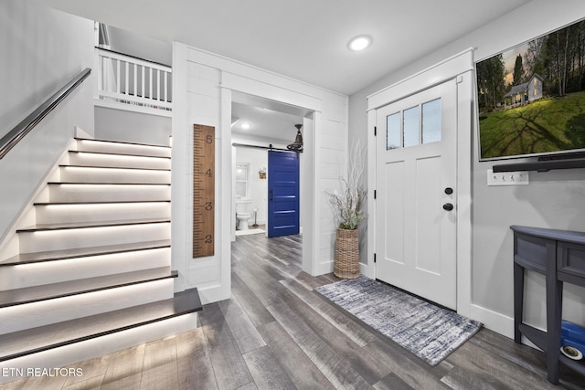entryway featuring a barn door, stairs, baseboards, dark wood-type flooring, and recessed lighting