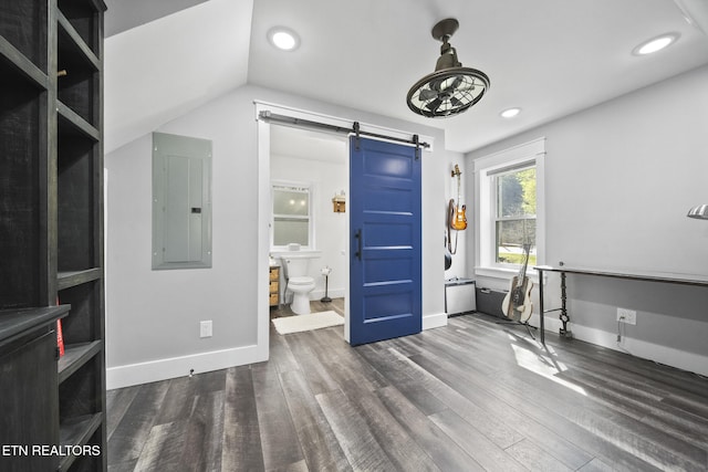 unfurnished bedroom featuring a barn door, electric panel, baseboards, dark wood-type flooring, and recessed lighting