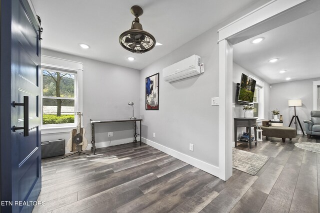 interior space featuring dark wood-type flooring, a wall mounted air conditioner, baseboards, and recessed lighting